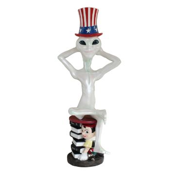 Alien mit amerikanischem Hut auf Pinocchiohocker lebensgroß